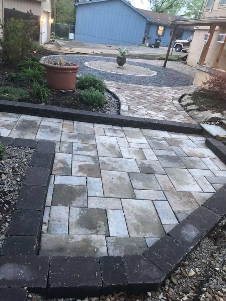 Patio made of gray tone pavers with a black paver outline.