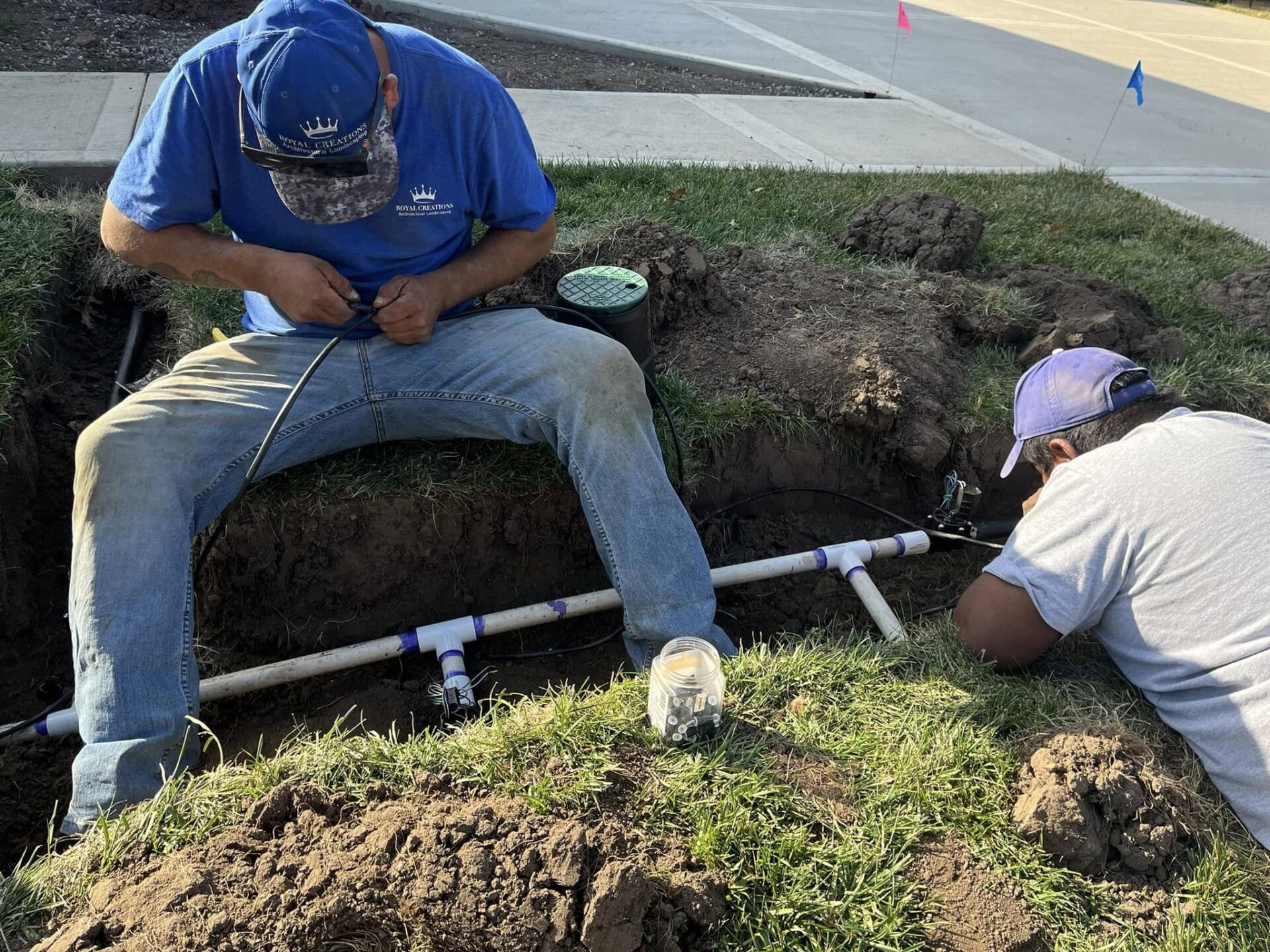 Two men installing an irrigation system in a trench.