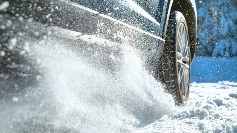 A car and tire showing snow on a snowy road.