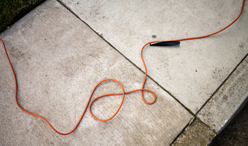 An orange extension cord on a sidewalk.