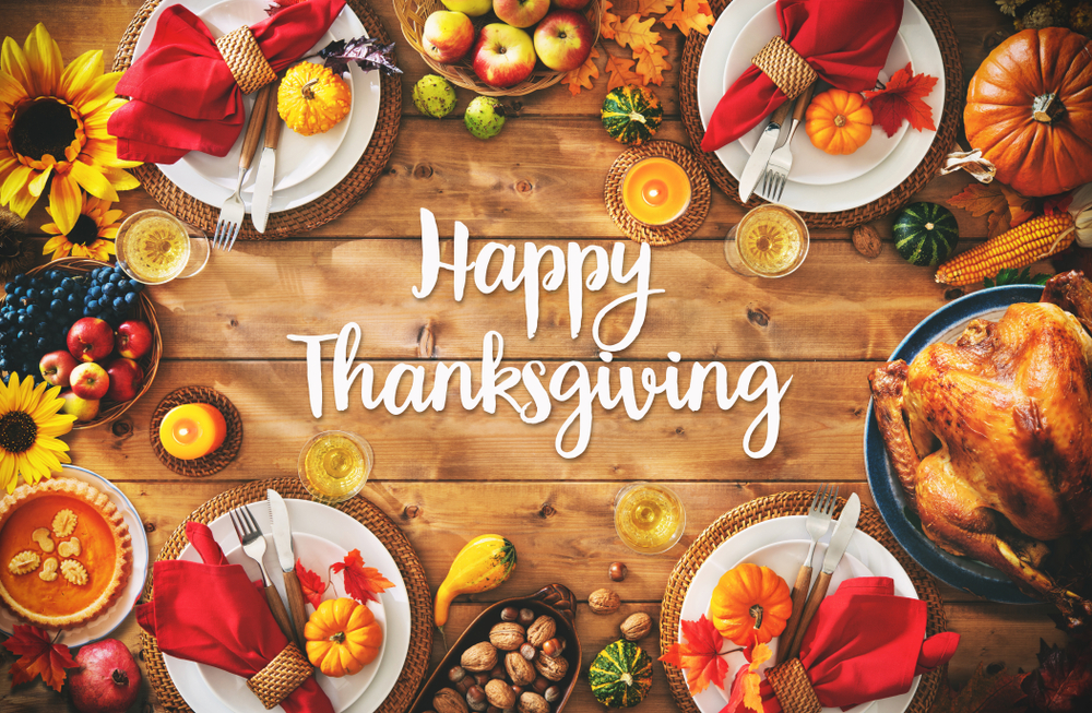 A  plank table wiith Thanksgiving decorations on it and the words Happy Thanksgiving