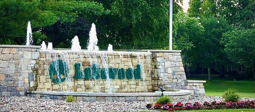 a rock sign with a fountain in it at the entrance of a neighborhood