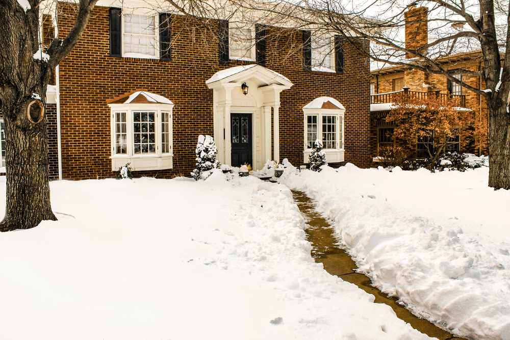 A brownstone house with snow all on the ground