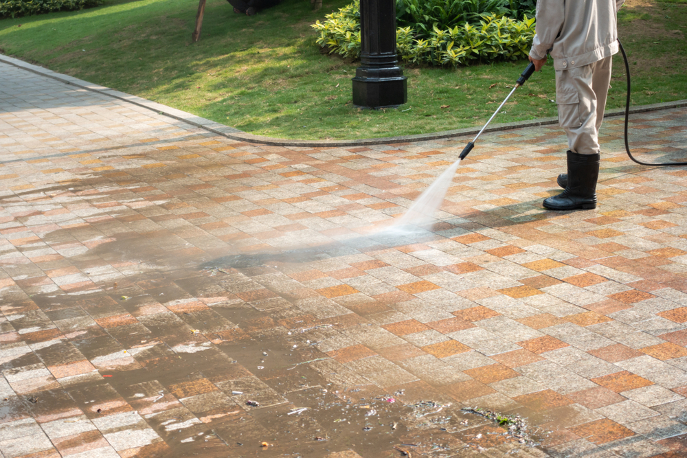 A man powerwashing a paves driveway