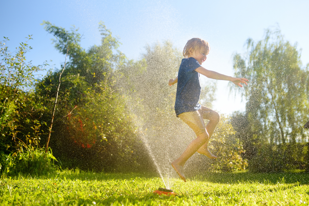 A child running through a sprinkler on a lawn