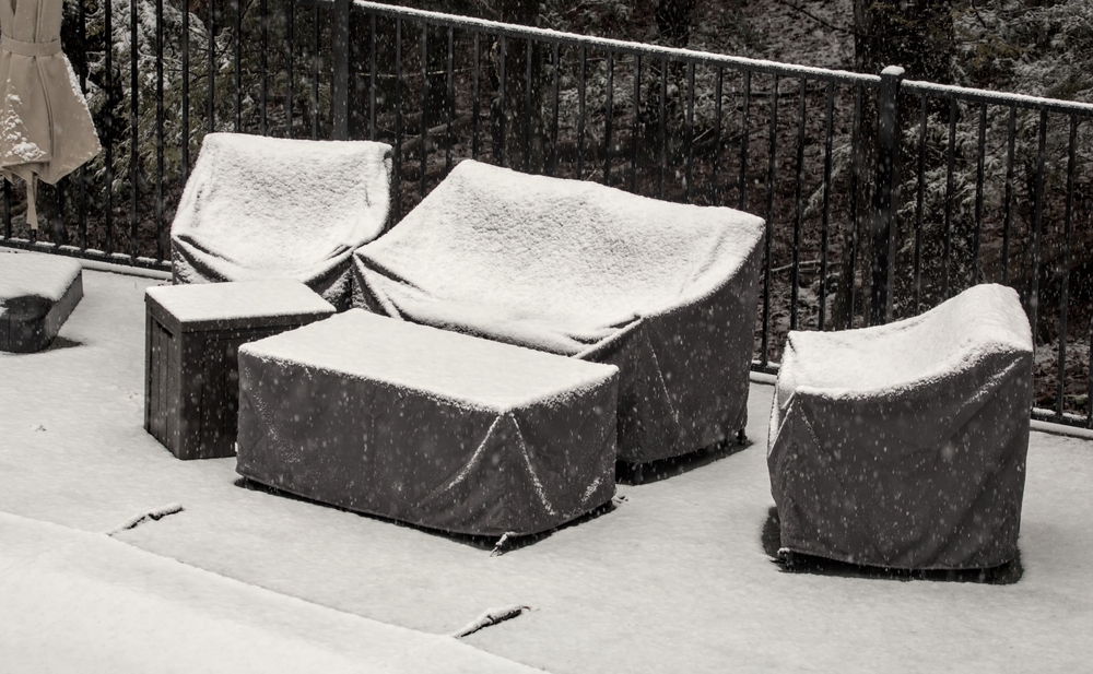 outdoor furniture with covers on it and a dusting of snow 